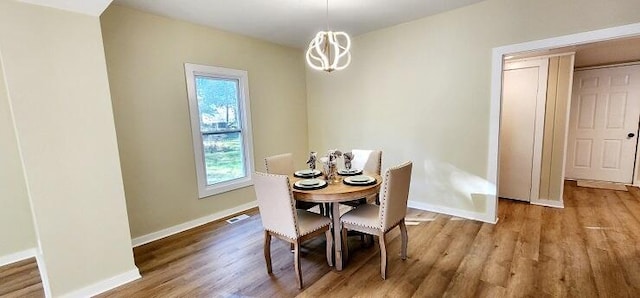 dining area featuring hardwood / wood-style flooring and an inviting chandelier