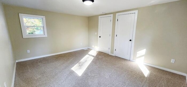 unfurnished bedroom with light carpet and two closets