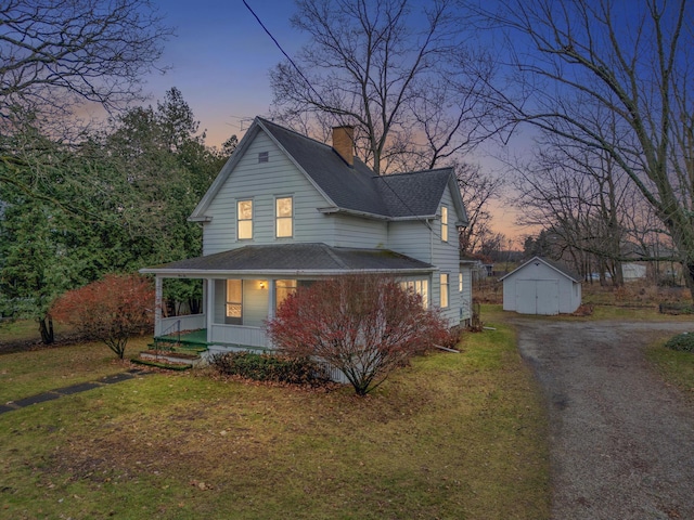 view of front of property featuring a porch, a garage, an outdoor structure, and a lawn