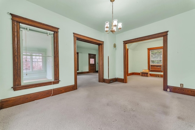 carpeted empty room with a notable chandelier