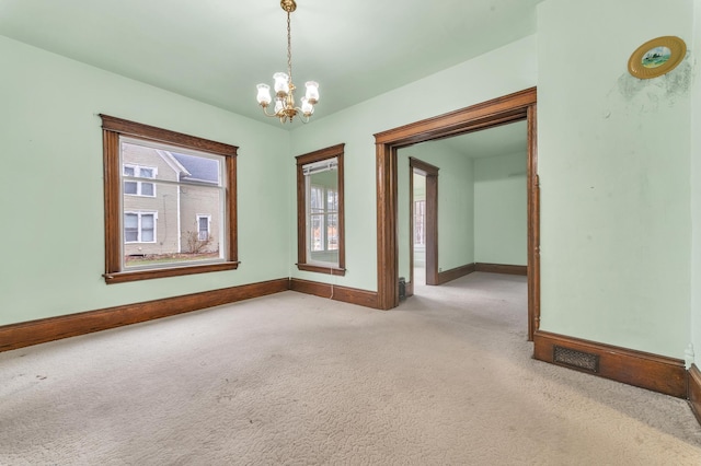 carpeted spare room featuring a notable chandelier