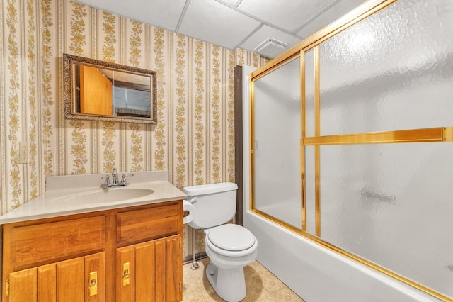 full bathroom with a paneled ceiling, vanity, enclosed tub / shower combo, tile patterned flooring, and toilet