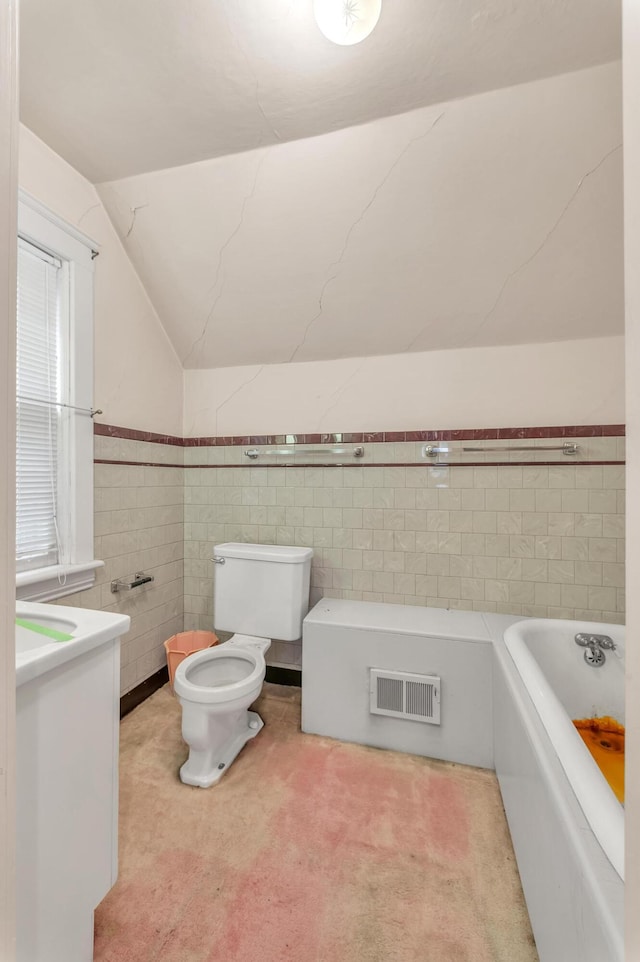 bathroom with vanity, vaulted ceiling, toilet, tile walls, and a tub