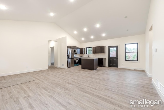 kitchen featuring high vaulted ceiling, light hardwood / wood-style floors, tasteful backsplash, a kitchen island, and stainless steel appliances