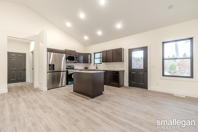 kitchen with sink, a center island, stainless steel appliances, high vaulted ceiling, and light hardwood / wood-style floors