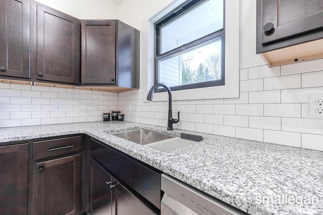 kitchen with tasteful backsplash, light stone counters, sink, and dark brown cabinets