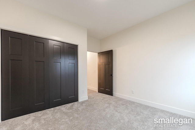 unfurnished bedroom with light carpet and a closet