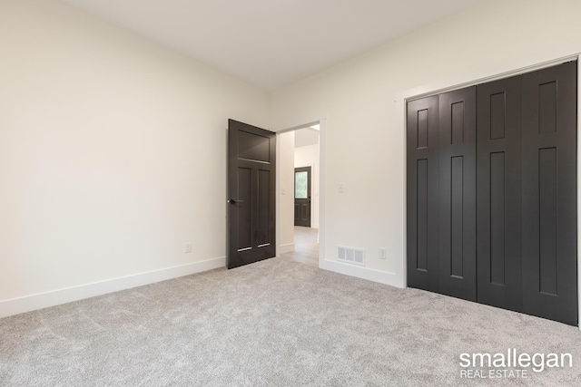 unfurnished bedroom featuring light colored carpet and a closet