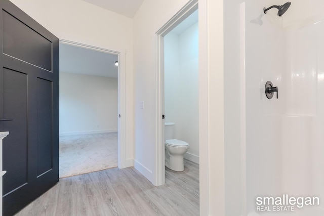 bathroom featuring walk in shower, wood-type flooring, and toilet