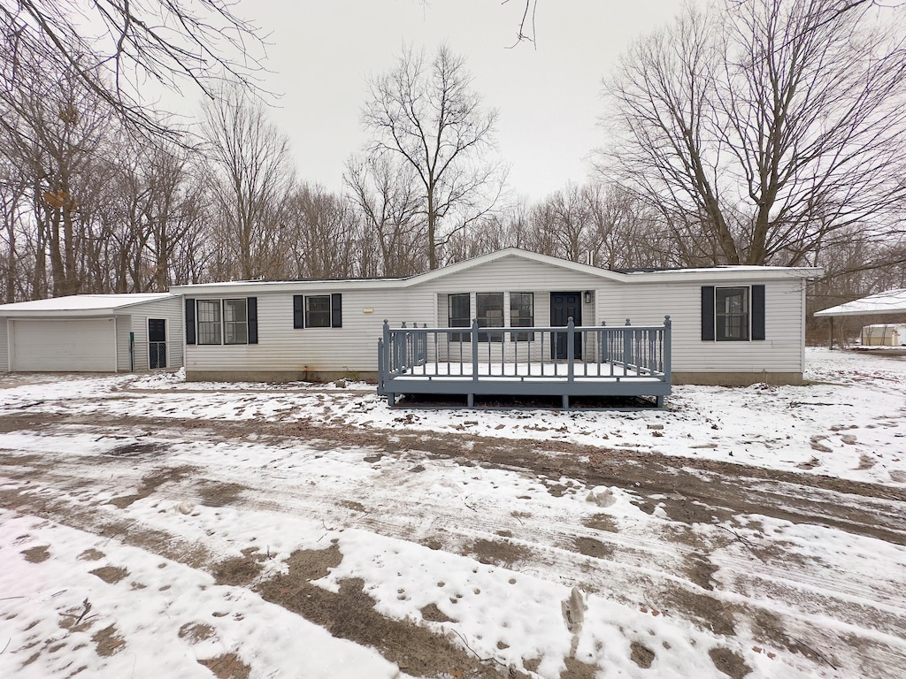 snow covered back of property featuring a garage