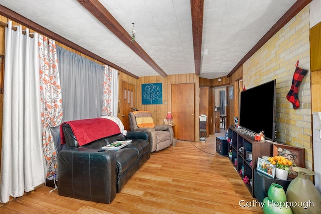 living room featuring light hardwood / wood-style floors, beam ceiling, and wooden walls