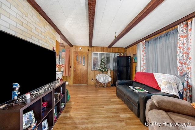 living room featuring beamed ceiling, light hardwood / wood-style flooring, brick wall, and wood walls