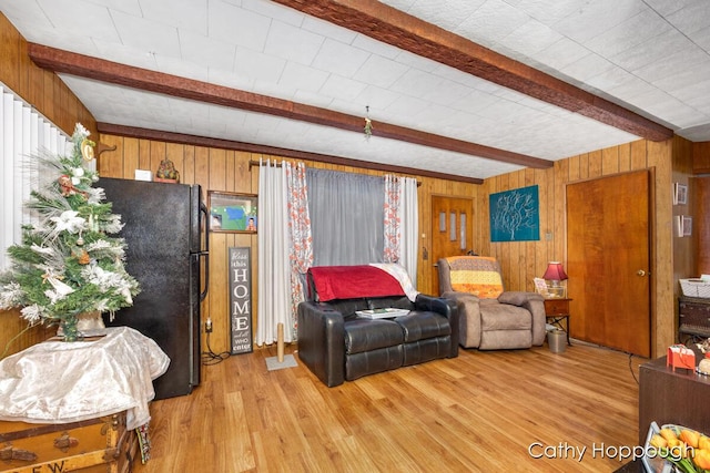 living room with beamed ceiling, light hardwood / wood-style floors, and wooden walls