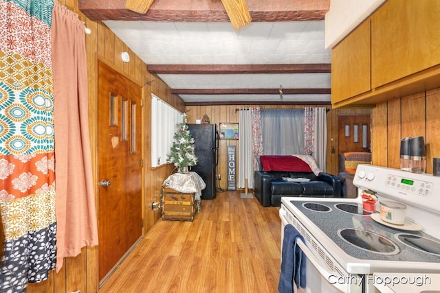 kitchen featuring black refrigerator, wooden walls, electric stove, beam ceiling, and light hardwood / wood-style flooring