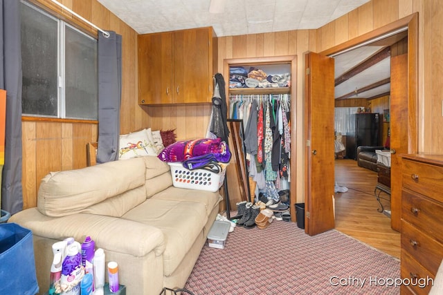 interior space featuring beam ceiling, wooden walls, and light hardwood / wood-style floors