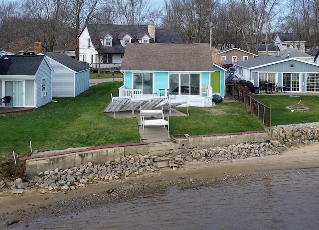 rear view of property featuring a lawn and a deck with water view