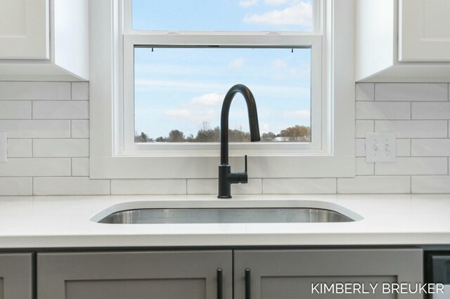 room details featuring white cabinets, backsplash, gray cabinetry, and sink