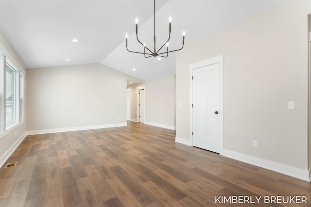 unfurnished dining area featuring wood-type flooring, vaulted ceiling, and an inviting chandelier