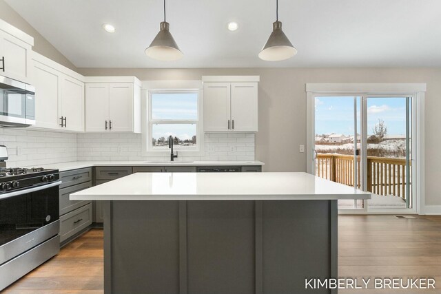 kitchen with gray cabinetry, sink, stainless steel appliances, pendant lighting, and white cabinets