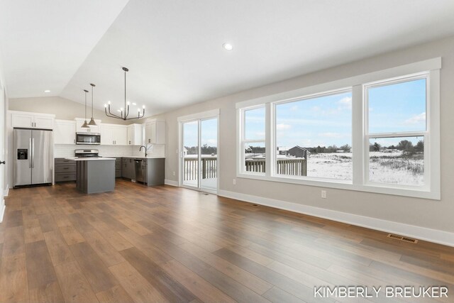 kitchen with stainless steel appliances, decorative light fixtures, a center island, dark hardwood / wood-style floors, and white cabinetry