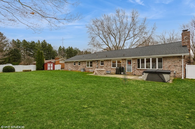 rear view of property featuring a lawn, a patio, a hot tub, and a storage shed