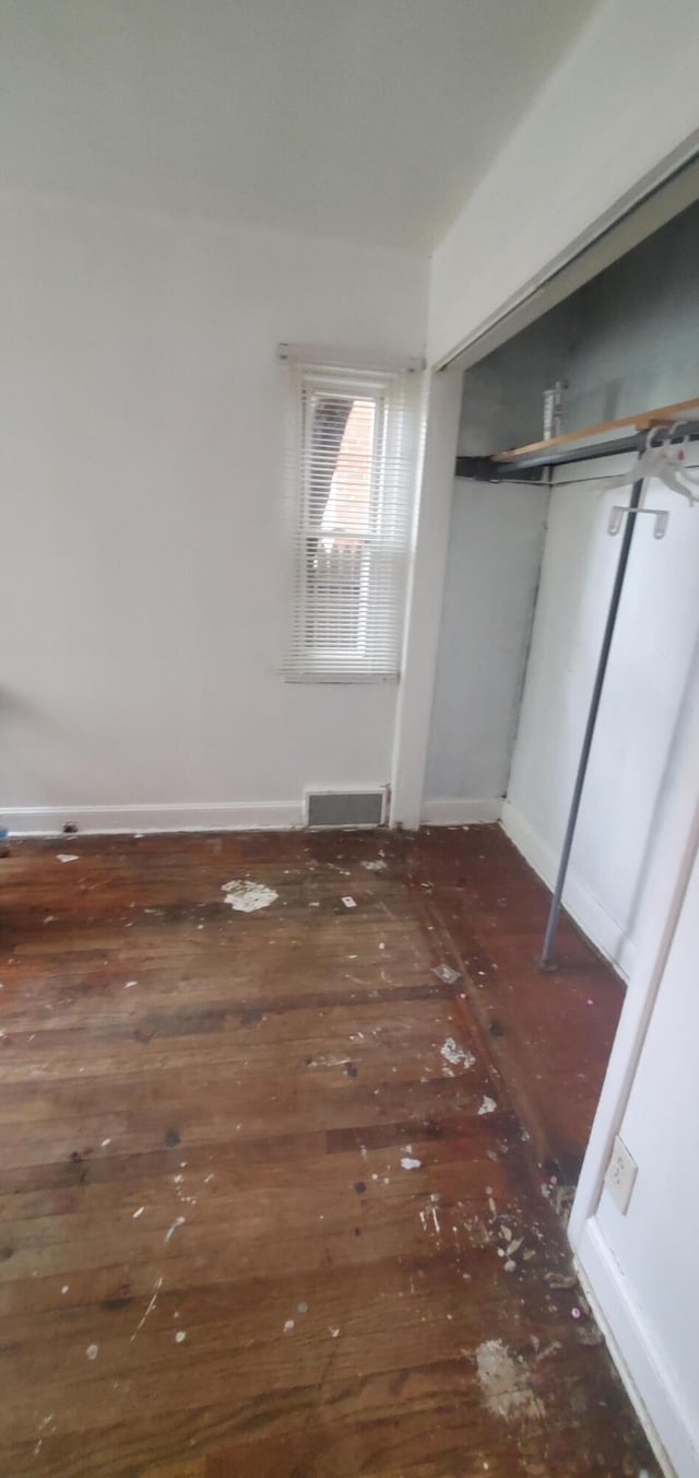 unfurnished bedroom featuring dark hardwood / wood-style flooring and a closet