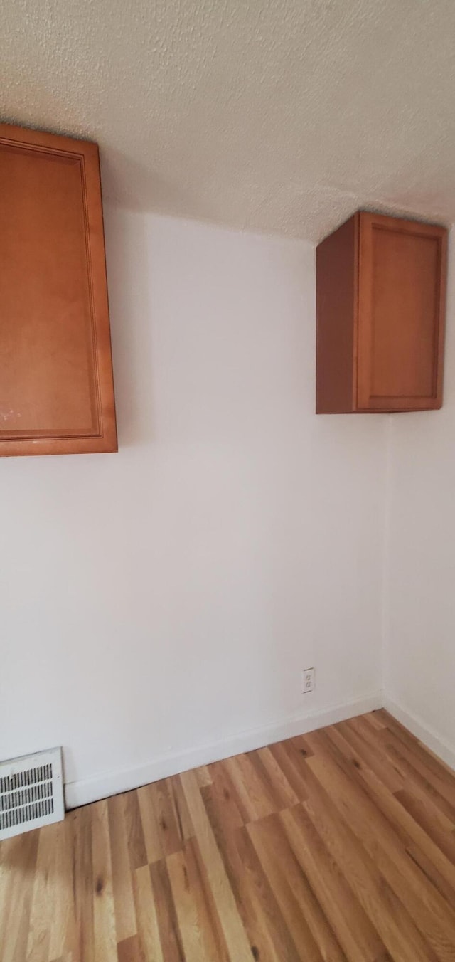 clothes washing area featuring hardwood / wood-style floors and a textured ceiling