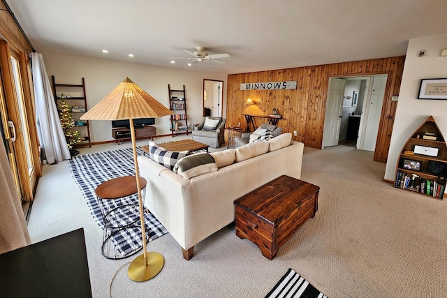 carpeted living room featuring ceiling fan and wood walls