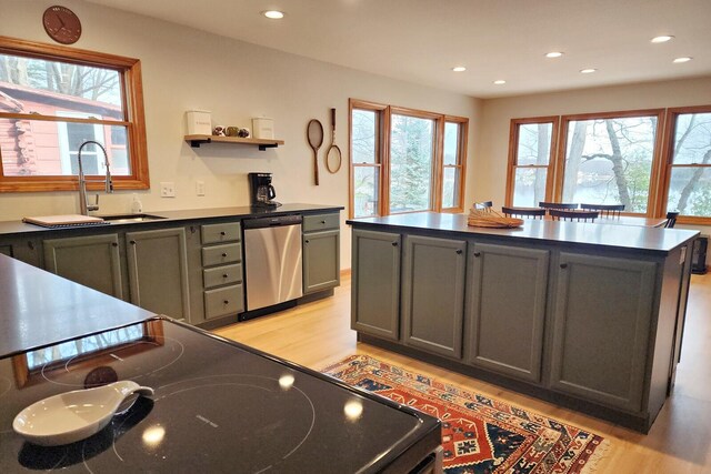 kitchen with sink, light hardwood / wood-style flooring, stainless steel dishwasher, stove, and a kitchen island