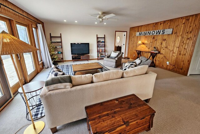 carpeted living room with ceiling fan and wooden walls