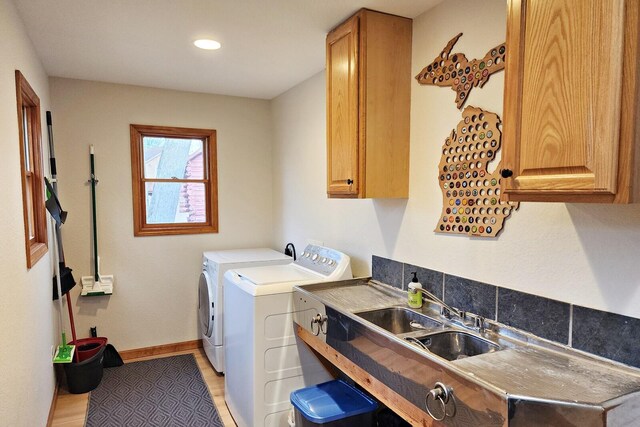 laundry room featuring cabinets, light wood-type flooring, separate washer and dryer, and sink