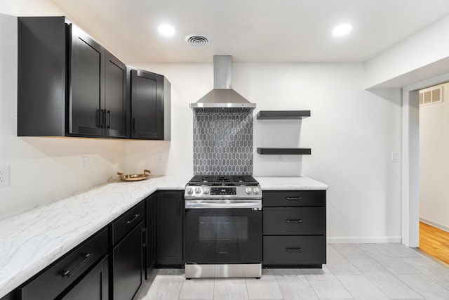 kitchen featuring light stone countertops, light wood-type flooring, wall chimney range hood, and stainless steel stove