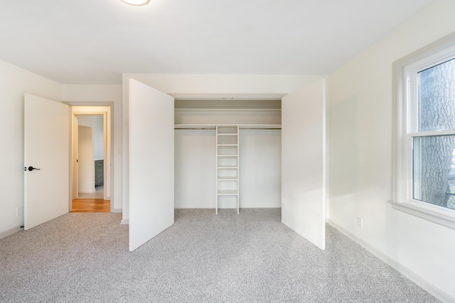 unfurnished bedroom with light carpet and a closet