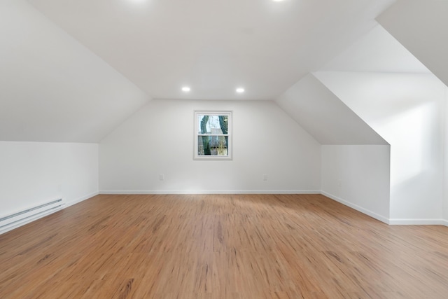 additional living space with light hardwood / wood-style flooring, a baseboard radiator, and lofted ceiling