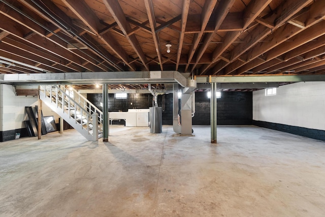 basement with gas water heater, heating unit, and washer and dryer