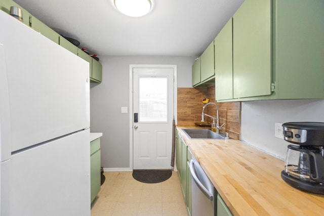 kitchen featuring butcher block counters, sink, green cabinetry, white refrigerator, and decorative backsplash