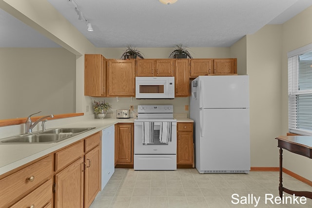 kitchen with rail lighting, sink, a textured ceiling, and white appliances