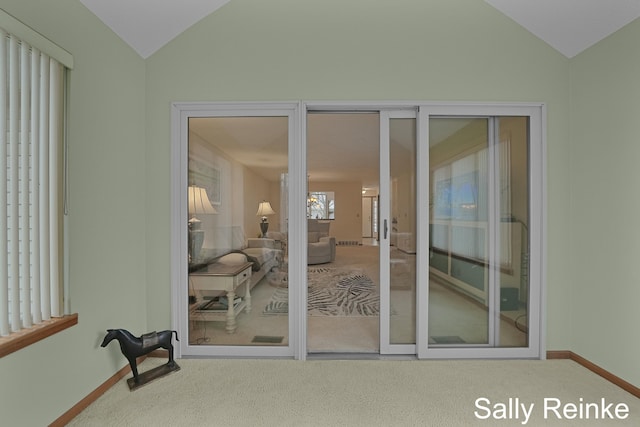 doorway to outside featuring an inviting chandelier, vaulted ceiling, and carpet