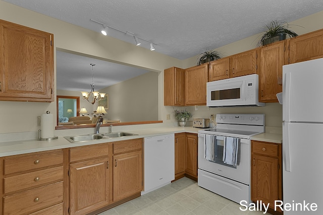 kitchen featuring a textured ceiling, white appliances, sink, decorative light fixtures, and an inviting chandelier