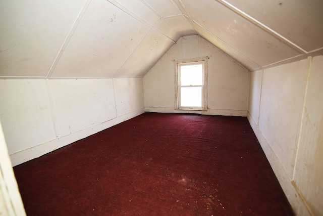 additional living space featuring dark carpet and lofted ceiling