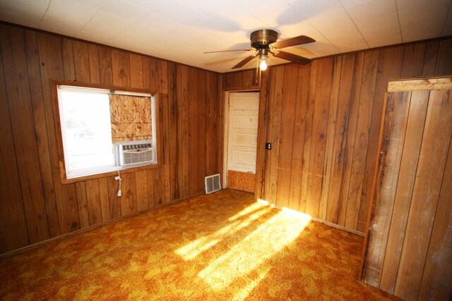 carpeted spare room with wood walls and cooling unit