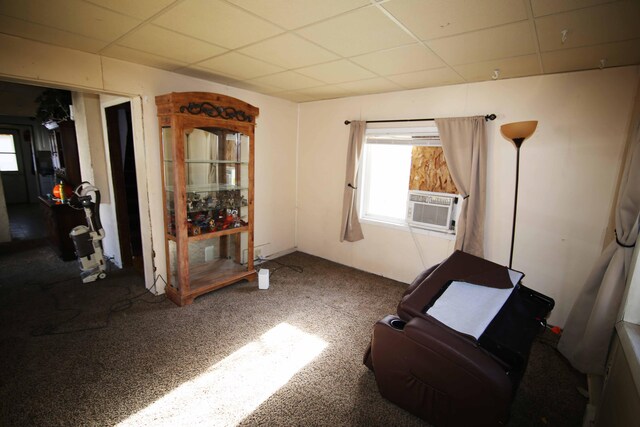 living area with carpet, a paneled ceiling, and cooling unit