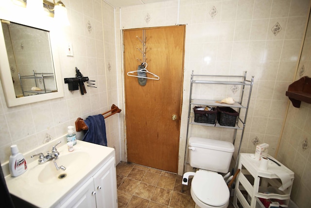 bathroom featuring tile patterned flooring, vanity, toilet, and tile walls