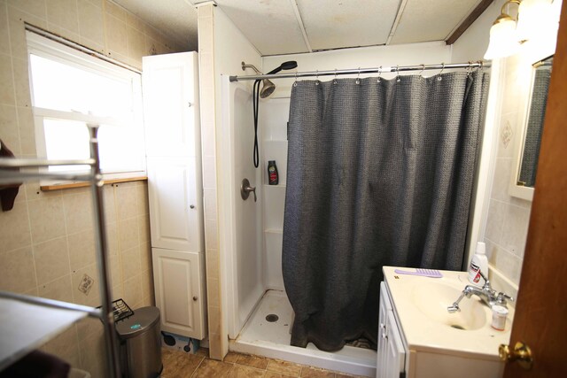 bathroom with a shower with curtain, tile walls, and vanity