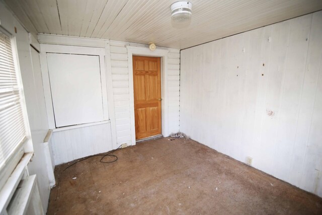 unfurnished room featuring wood walls and concrete floors