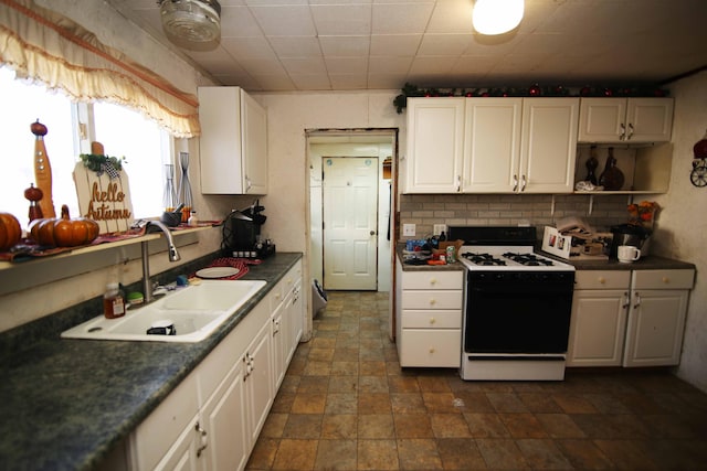 kitchen featuring white range oven, white cabinetry, tasteful backsplash, and sink