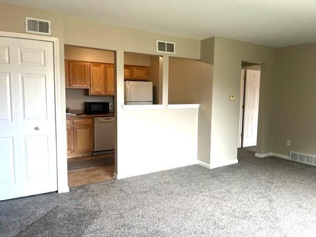 kitchen featuring dark colored carpet and white appliances