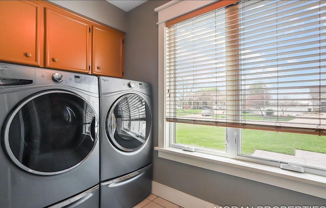 clothes washing area with cabinets, independent washer and dryer, and light tile patterned floors