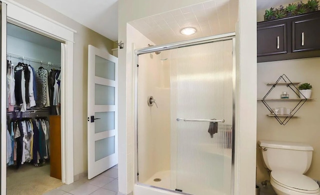 bathroom featuring tile patterned floors, toilet, and a shower with shower door