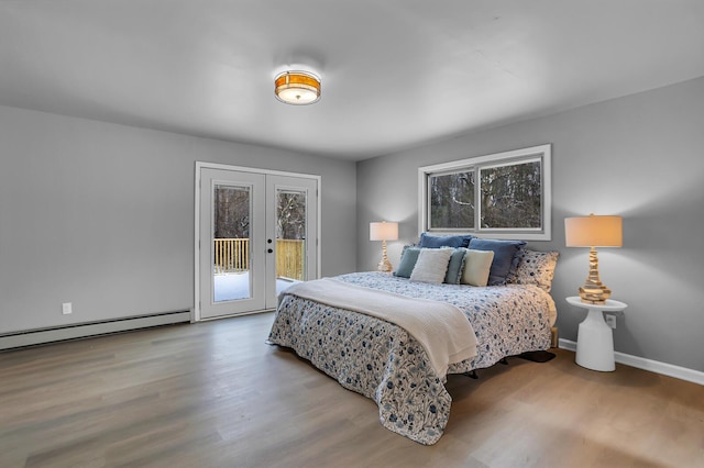 bedroom with access to outside, multiple windows, a baseboard heating unit, and hardwood / wood-style flooring